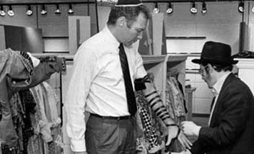 A Chabad student helps a Jew put on tefillin in a store in Manhattan
