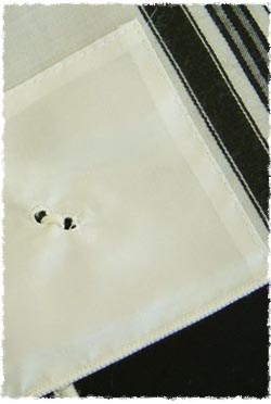 The two holes that the fringes are sprung through on the Tzitzit